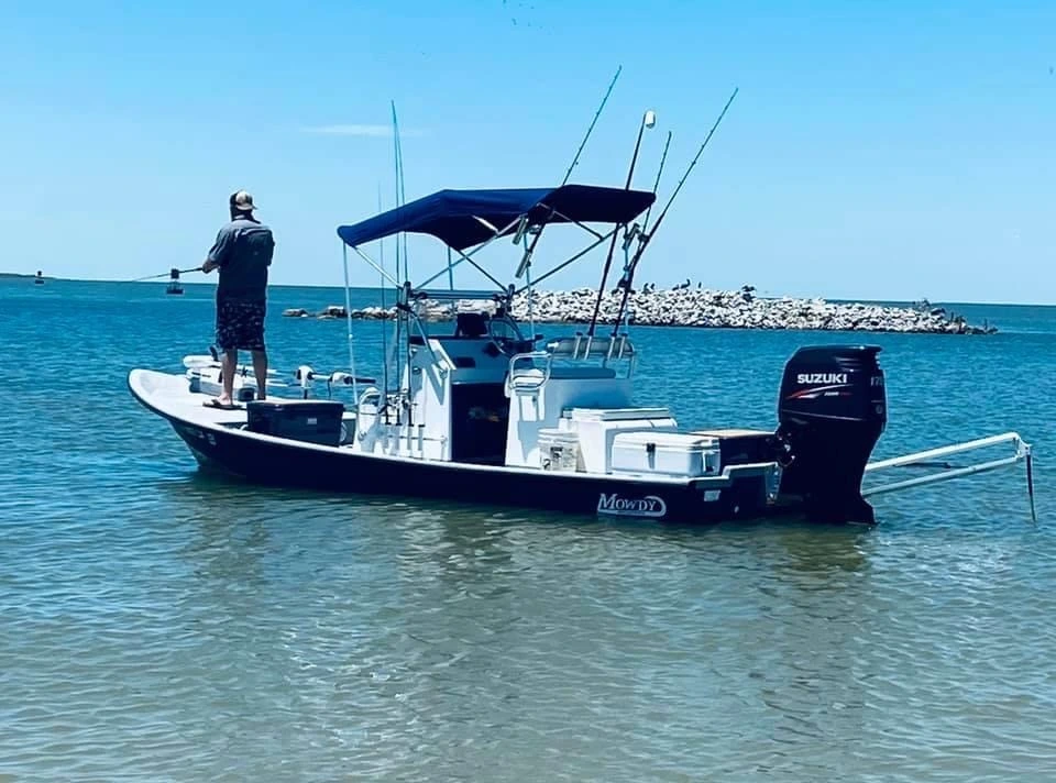 An angler on the bow of a Mowdy bay boat under a navy Canvas USA® Bimini T™