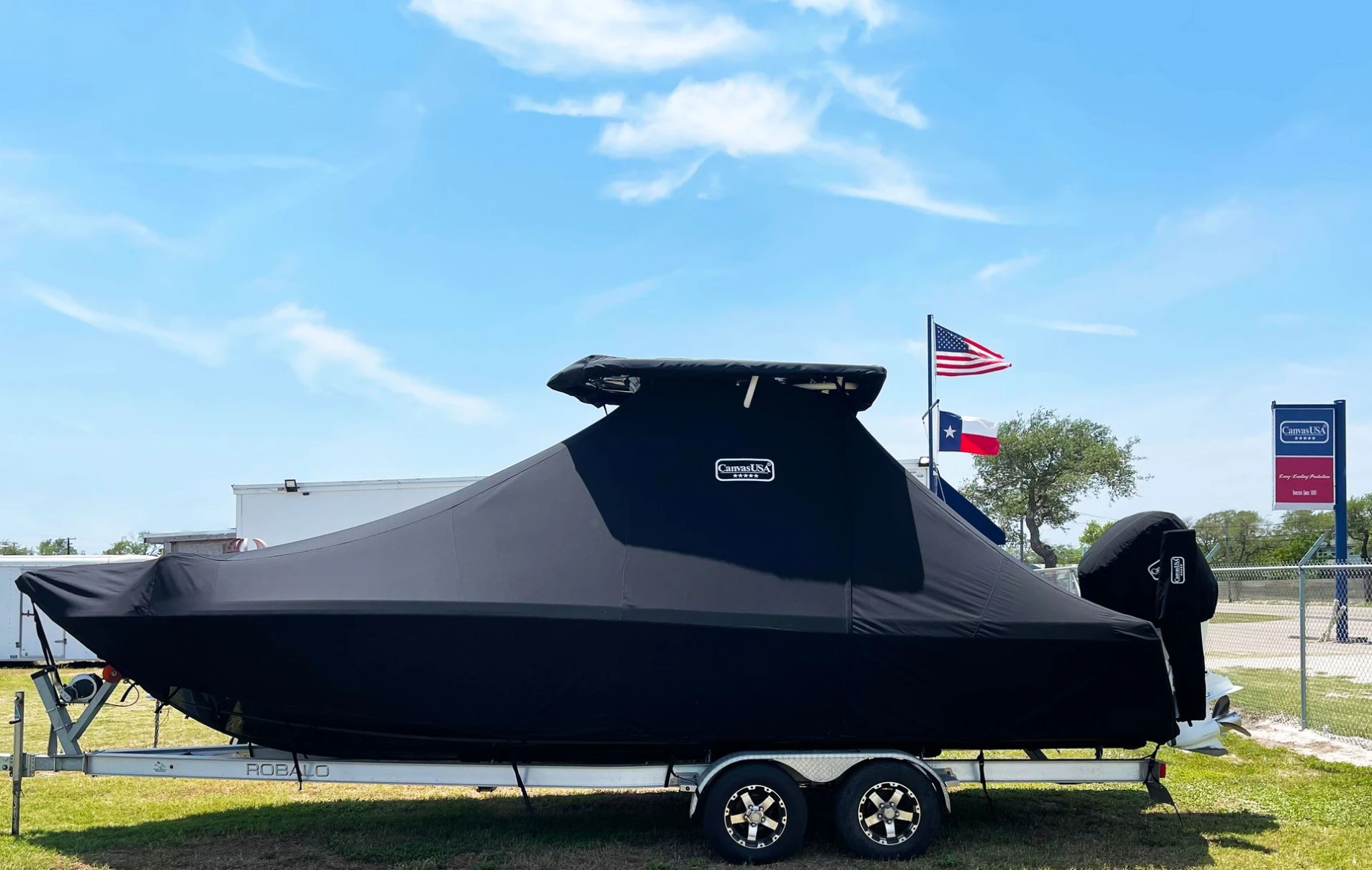 A center-console boat under a fitted black driveway full cover on its trailer