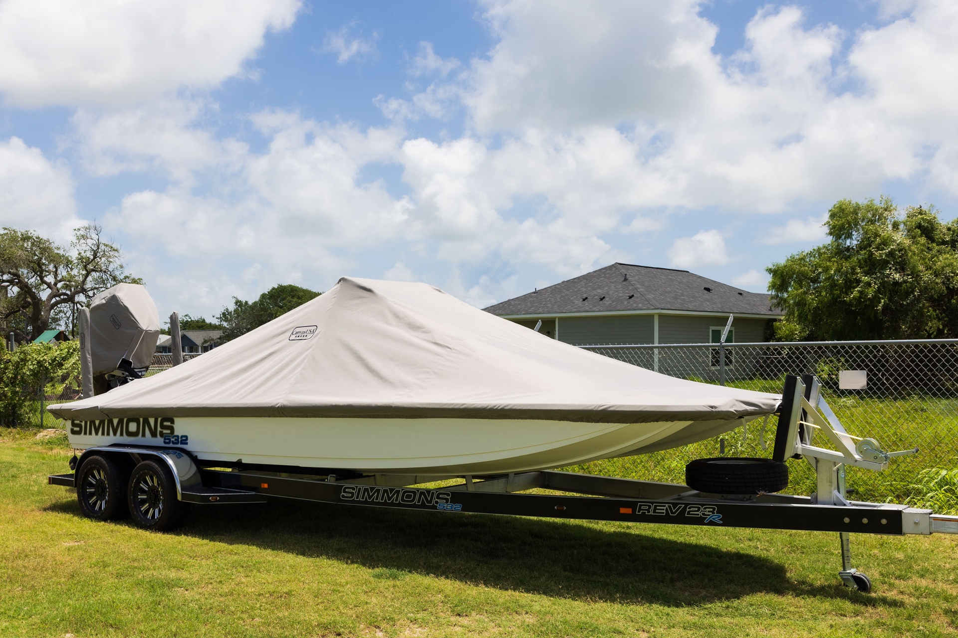 A boat under a fitted gray Canvas USA® cover on its trailer