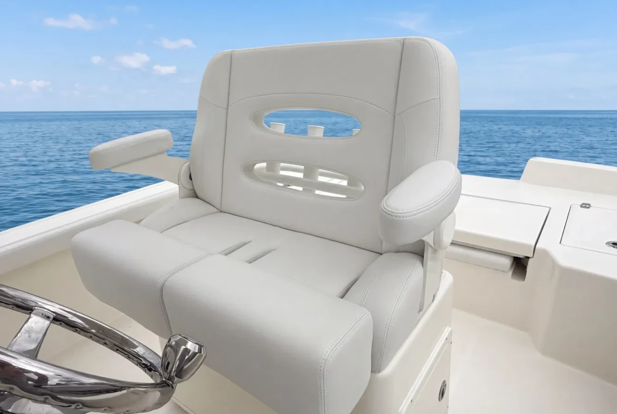 A white Canvas USA® helm chair at the wheel of a boat on open water