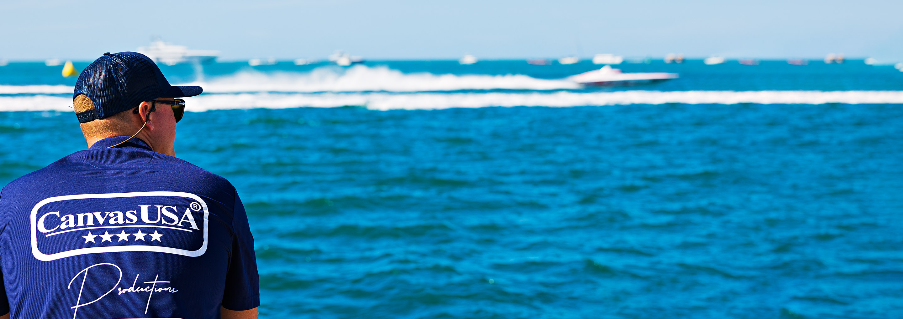 Man in a Canvas USA® shirt watching powerboats race offshore