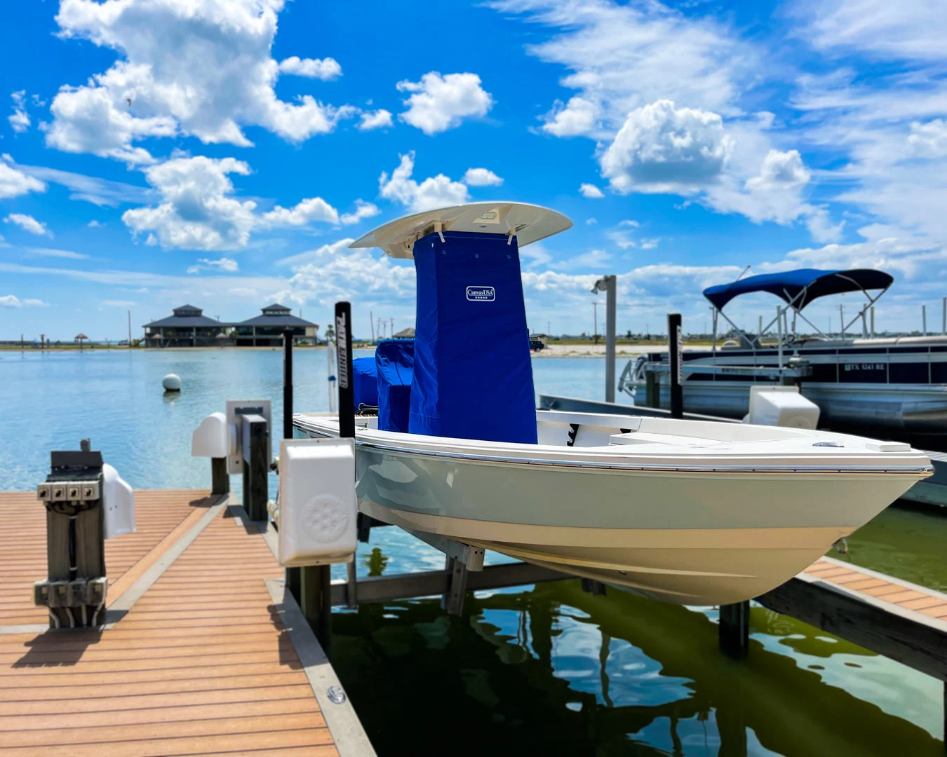 Bay boat on a dock lift with a blue console cover