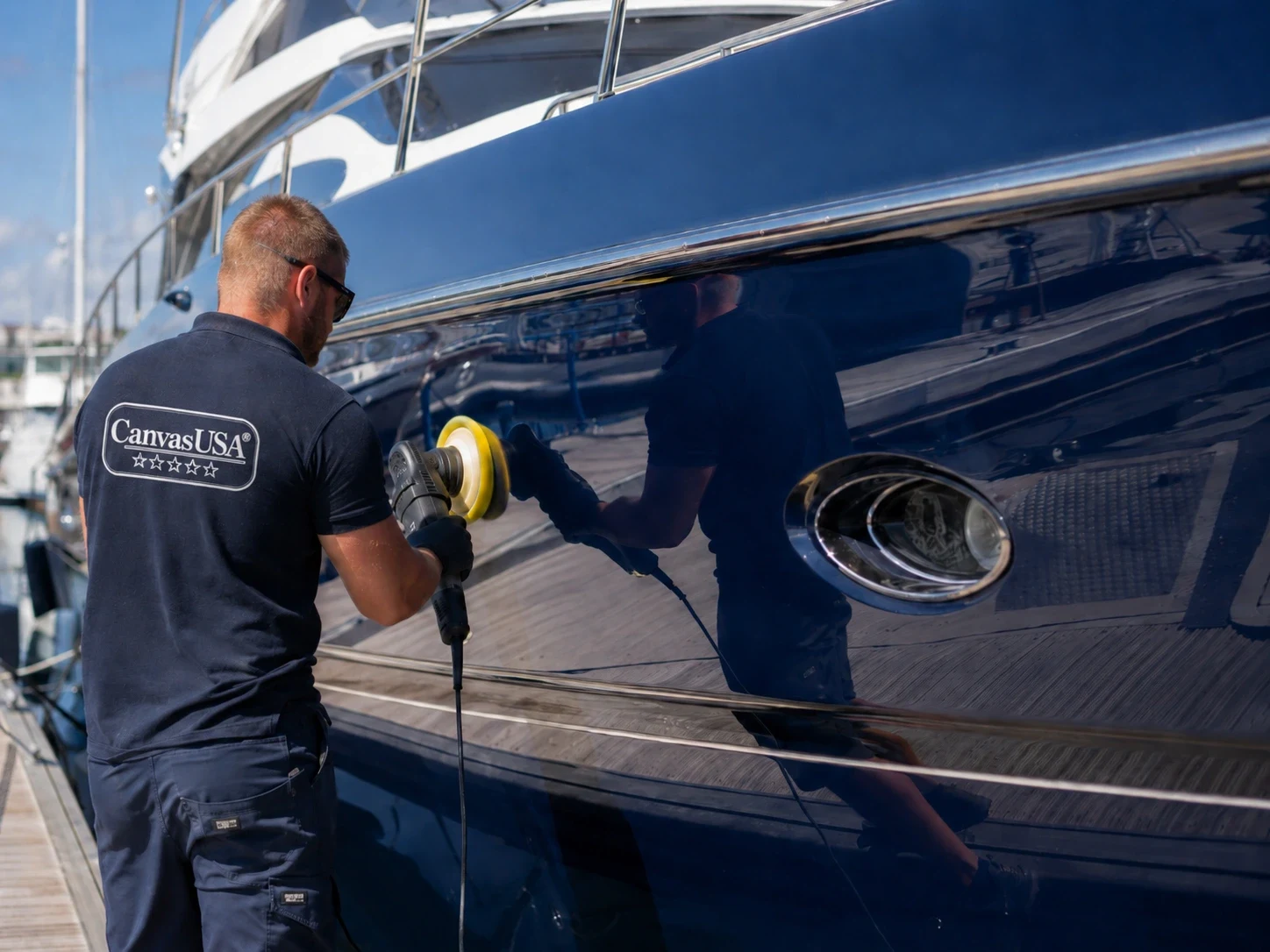 Canvas USA® crew member polishing a navy yacht hull