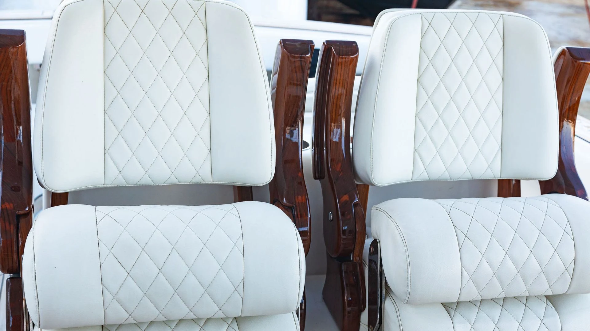 Diamond-stitched white captain's chairs with wood armrests