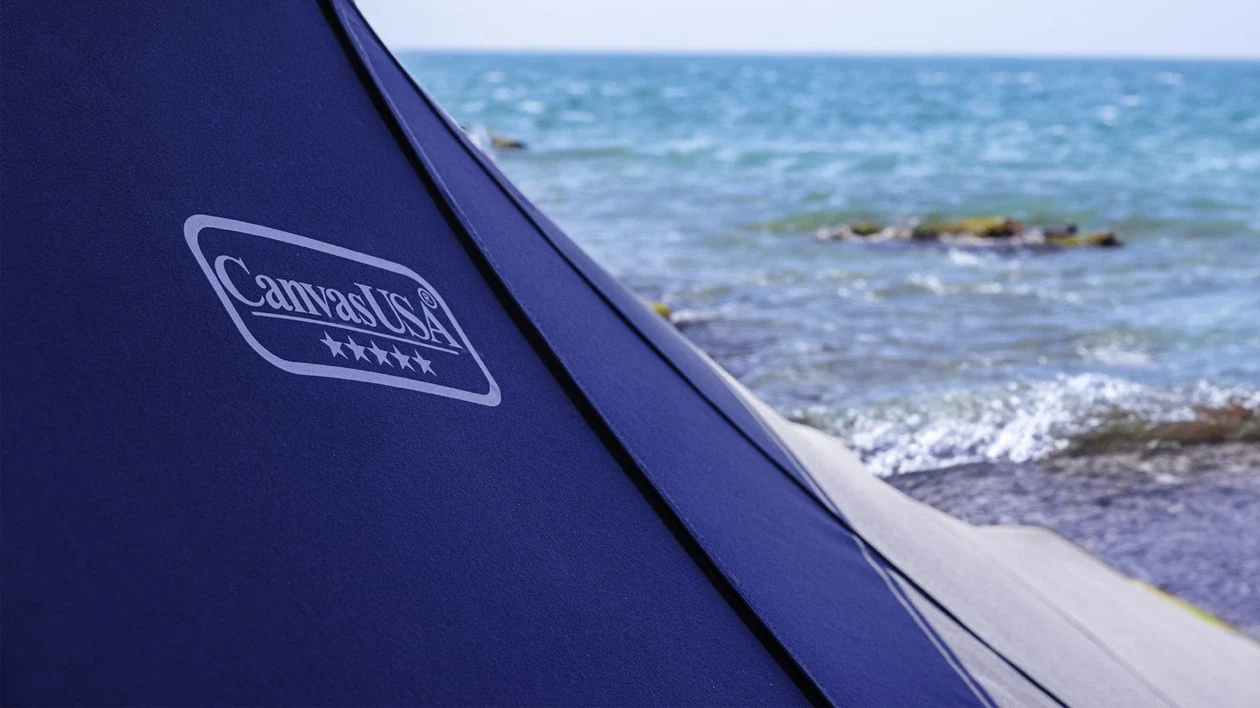 Canvas USA® logo on a navy canvas cover at the water's edge